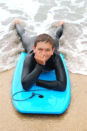 Smiling teenage surfer in a wetsuit laying on his bodyboard on the beach. Stock Photo - Budget Royalty-Free & Subscription, Code: 400-04208392