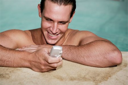 swimming pool leaning on edge - Male texting on mobile phone in swimming pool on holiday Stock Photo - Budget Royalty-Free & Subscription, Code: 400-04208483
