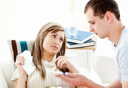 Loving boyfriend holding a thermometer of his ill girlfriend in the living room Stock Photo - Budget Royalty-Free & Subscription, Code: 400-04208857
