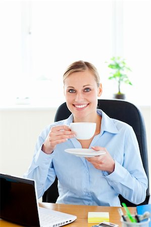 simsearch:400-05749531,k - Cheerful young businesswoman drinking coffee smiling at the camera in the office Stock Photo - Budget Royalty-Free & Subscription, Code: 400-04209355