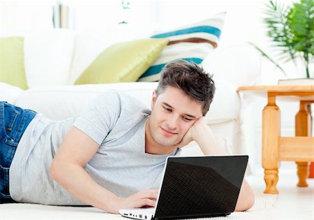 simsearch:400-05209351,k - Positive young man using his laptop lying on the floor at home Stock Photo - Budget Royalty-Free & Subscription, Code: 400-04209848