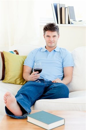 Charming man holding a wineglass sitting on the sofa smiling at the camera in the living-room Stock Photo - Budget Royalty-Free & Subscription, Code: 400-04209852