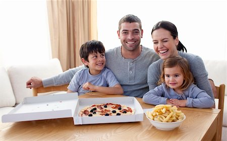 Happy young family eating a pizza in the living-room at home Stock Photo - Budget Royalty-Free & Subscription, Code: 400-04200317