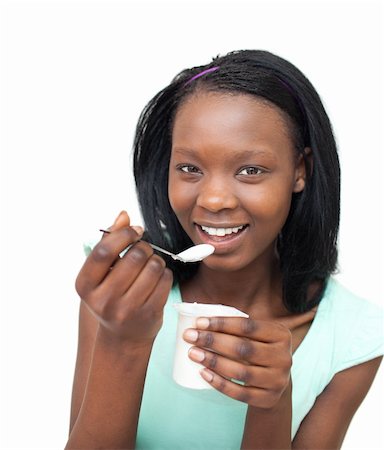 Cheerful young woman eating a yogurt against a white background Stock Photo - Budget Royalty-Free & Subscription, Code: 400-04201195