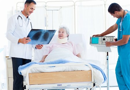 Smiling doctor showing an x-ray to a female patient lying on a hospital bed Stock Photo - Budget Royalty-Free & Subscription, Code: 400-04201450