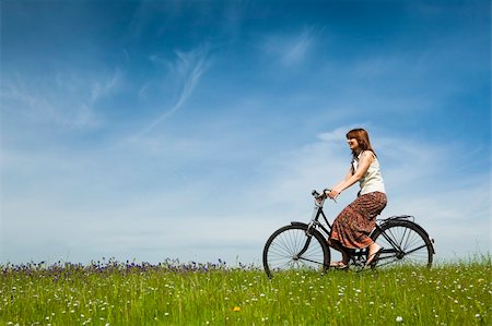 simsearch:400-04201795,k - Happy young woman on a green meadow riding a bicycle Fotografie stock - Microstock e Abbonamento, Codice: 400-04201793