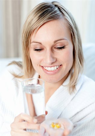 simsearch:400-05892402,k - Sick caucasian woman holding a glass of water and pills sitting on a sofa Stock Photo - Budget Royalty-Free & Subscription, Code: 400-04202192