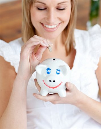 simsearch:614-03903063,k - Cheerful woman saving money in a piggy-bank at home Stock Photo - Budget Royalty-Free & Subscription, Code: 400-04202242