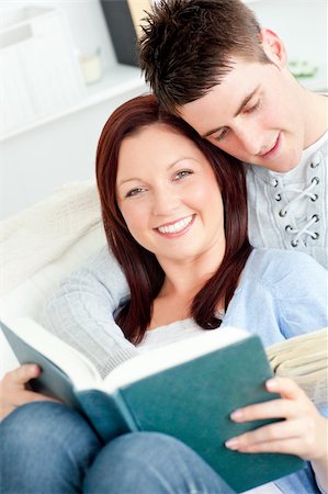 divert - Charming young couple reading a book lying on the sofa in the living-room Stock Photo - Budget Royalty-Free & Subscription, Code: 400-04214948