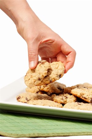 simsearch:400-06643567,k - A plate of oatmeal chocolate chip cookies with a hand taking two. Stockbilder - Microstock & Abonnement, Bildnummer: 400-04217118