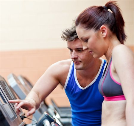 simsearch:400-05677914,k - Pretty athletic woman standing on a running machine with her personal coach in a fitness center Stock Photo - Budget Royalty-Free & Subscription, Code: 400-04217223
