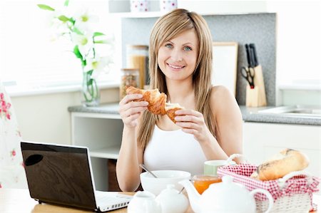 simsearch:400-05741872,k - Smiling woman having breakfast in front of the laptop in the kitchen at home Stockbilder - Microstock & Abonnement, Bildnummer: 400-04217658