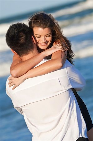 simsearch:400-06751687,k - A young man and woman happy having fun and embracing as a romantic couple on a beach Stock Photo - Budget Royalty-Free & Subscription, Code: 400-04219034