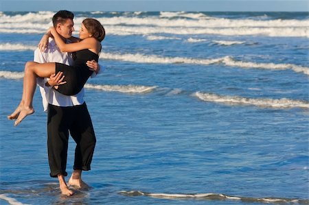 simsearch:400-06751687,k - A young man carrying his girlfriend as a romantic couple through the surf on a beautiful beach Stock Photo - Budget Royalty-Free & Subscription, Code: 400-04219035
