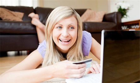 simsearch:400-04709946,k - Delighted young woman holding a card on the floor smiling at the camera in the living room Stockbilder - Microstock & Abonnement, Bildnummer: 400-04210144