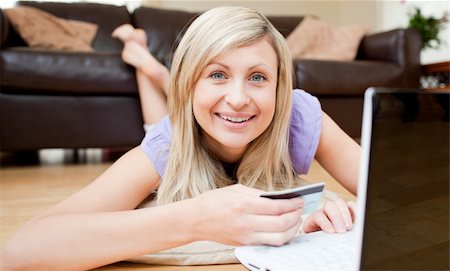 simsearch:400-04709946,k - Beautiful young woman holding a card on the floor smiling at the camera in the living room Stockbilder - Microstock & Abonnement, Bildnummer: 400-04210145
