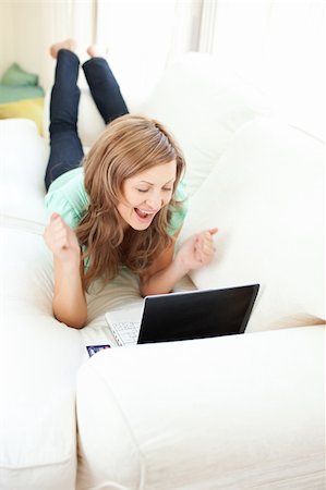 simsearch:400-06419734,k - Enthusiastic caucasian woman looking at her laptop on the sofa at home Stock Photo - Budget Royalty-Free & Subscription, Code: 400-04210166