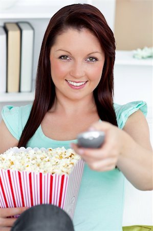 simsearch:400-04212407,k - Cute caucasian woman holding a remote and popcorn looking at the camera in the living-room Stock Photo - Budget Royalty-Free & Subscription, Code: 400-04210845