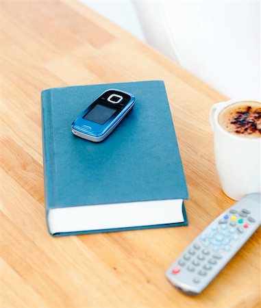 Close-up of a book,cellphone,remote and cup of coffee on the table in a house Stock Photo - Budget Royalty-Free & Subscription, Code: 400-04210859