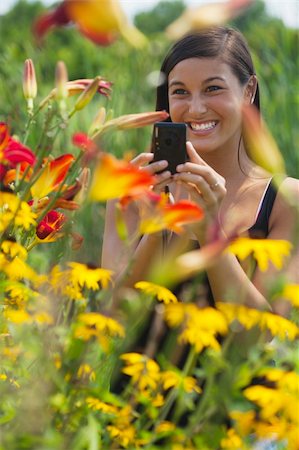 edbockstock (artist) - Cute Asian woman smiles while taking pictures of flowers with a small camera. Vertical shot. Photographie de stock - Aubaine LD & Abonnement, Code: 400-04211612