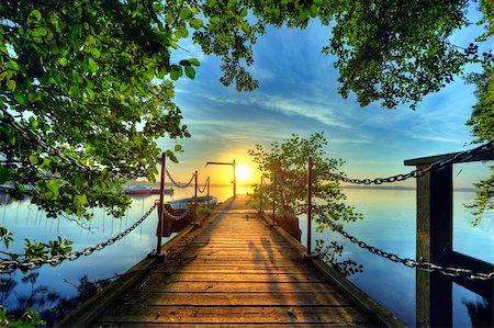 simsearch:400-09066555,k - sunrise at a pier with a boat and branch hanging out over the water Fotografie stock - Microstock e Abbonamento, Codice: 400-04211695