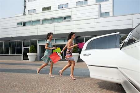 fashion shopping bags glamorous outdoor - two women running into limousine with shopping bags. Horizontal shape, full length Stock Photo - Budget Royalty-Free & Subscription, Code: 400-04211836