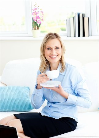 simsearch:400-05741872,k - Smiling businesswoman drinking coffee sitting on a sofa at home Stock Photo - Budget Royalty-Free & Subscription, Code: 400-04212376