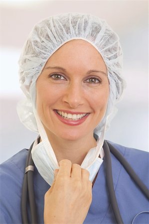 doctor with cap and mask - Portrait of smiling young woman doctor in scrubs pulling on mask Stock Photo - Budget Royalty-Free & Subscription, Code: 400-04212470