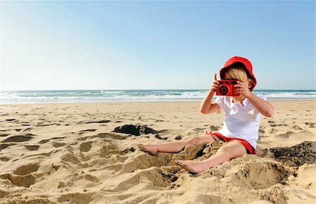Adorable little girl takes pictures with her red camera on the beach Foto de stock - Super Valor sin royalties y Suscripción, Código: 400-04212758