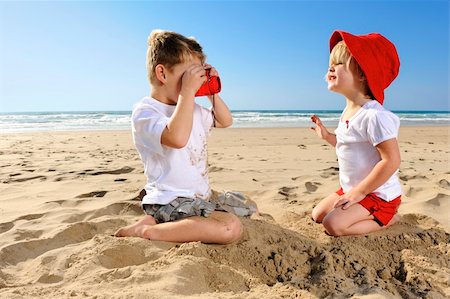 Cute young girl poses for her brother on the beach Foto de stock - Super Valor sin royalties y Suscripción, Código: 400-04212759