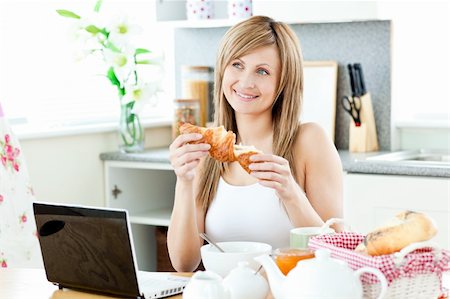 simsearch:400-05741872,k - Smiling woman having breakfast in front of the laptop in the kitchen at home Stockbilder - Microstock & Abonnement, Bildnummer: 400-04213035