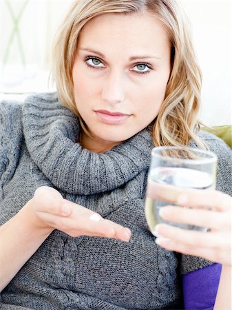 Sick depressed woman holding pills and water looking at the camera in the living room Stock Photo - Budget Royalty-Free & Subscription, Code: 400-04213091