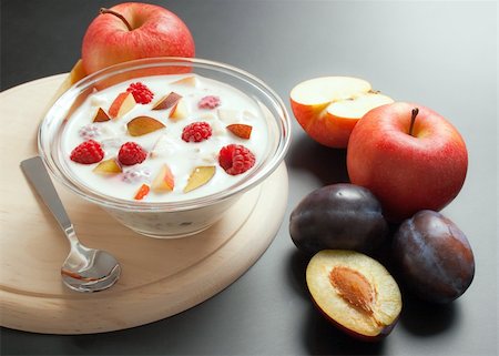 Glass bowl filled with yogurt mixed with fruit pieces arranged with spoon and some fruits around Stock Photo - Budget Royalty-Free & Subscription, Code: 400-04213447