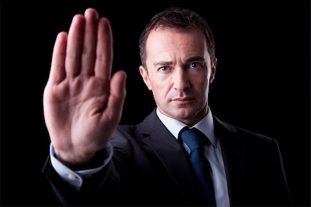 simsearch:400-04213571,k - Businessman with his hand raised in signal to stop, isolated on black background, Studio shot Foto de stock - Royalty-Free Super Valor e Assinatura, Número: 400-04213571