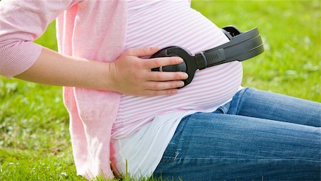 pregnant music - Joyful pregnant woman with headphones on her belly sitting on the grass Stock Photo - Budget Royalty-Free & Subscription, Code: 400-04224462