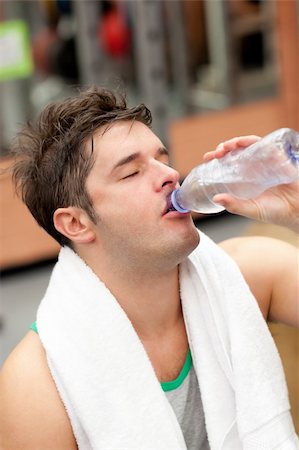 simsearch:400-05677914,k - exhausted man drinking water with towel around the neck after a training in a fitness centre Stock Photo - Budget Royalty-Free & Subscription, Code: 400-04224751