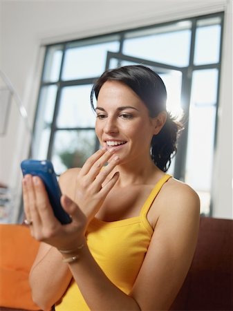 mid adult woman sitting on sofa, getting good news on mobile phone. Vertical shape, side view, waist up Stock Photo - Budget Royalty-Free & Subscription, Code: 400-04225233