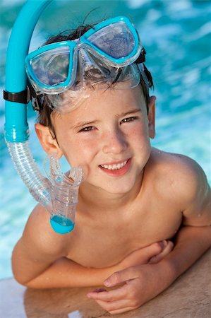 smile as mask for boy - A happy young boy child relaxing on the side of a swimming pool wearing blue goggles and snorkel Stock Photo - Budget Royalty-Free & Subscription, Code: 400-04226836