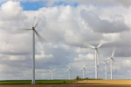A farm of wind turbines or windmills providing alternative sustainable green energy, situated in a field of sunflowers Photographie de stock - Aubaine LD & Abonnement, Code: 400-04226842