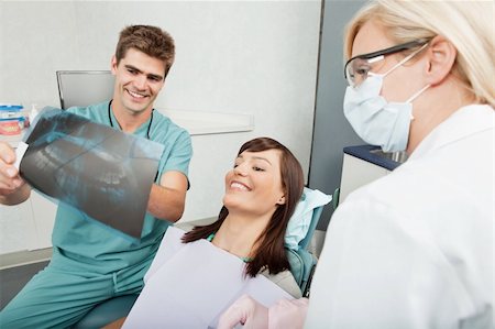 Smiling male dentist explaining the details of x-ray to a beautiful female patient Stock Photo - Budget Royalty-Free & Subscription, Code: 400-04227112