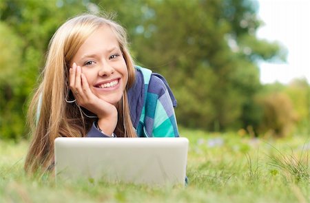 simsearch:6109-06003537,k - beautiful young student girl lying on grass with laptop and books, looking into the camera and smiling Fotografie stock - Microstock e Abbonamento, Codice: 400-04227646