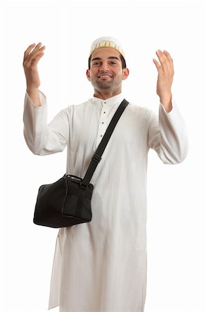 Ethnic mixed race man wearing white embroidered robe  and topi hat and carrying black shoulder bag and arms raised in praise or joy Stock Photo - Budget Royalty-Free & Subscription, Code: 400-04229037
