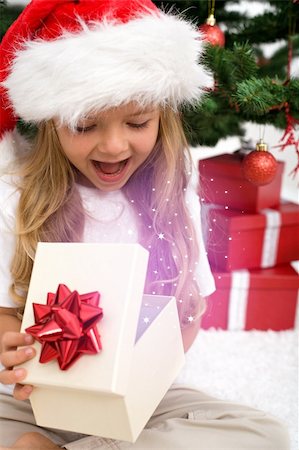 simsearch:400-06477682,k - Excited little girl opening christmas present with magical glow in front of the fir tree - closeup Stock Photo - Budget Royalty-Free & Subscription, Code: 400-04229182