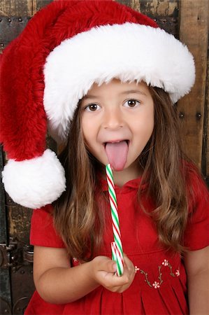 dreaming about eating - Cute brunette girl eating Christmas candy and sticking her tongue out Foto de stock - Super Valor sin royalties y Suscripción, Código: 400-04229453