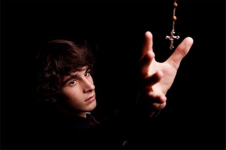 young men with arm raised, trying to grab a crucifix, isolated on black, studio shot Foto de stock - Super Valor sin royalties y Suscripción, Código: 400-04220492