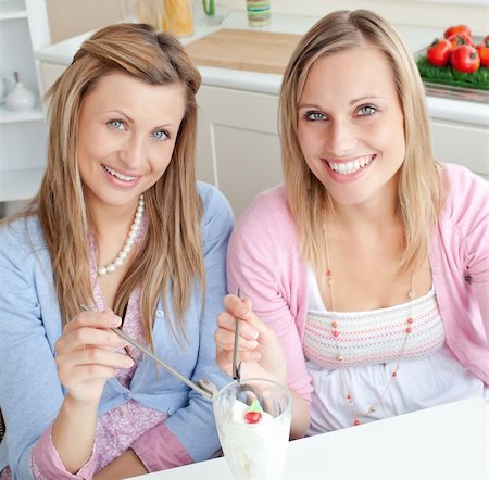 simsearch:400-04729451,k - Cheerful friends eating an ice cream and smiling at the camera in the kitchen at home Stock Photo - Budget Royalty-Free & Subscription, Code: 400-04220772