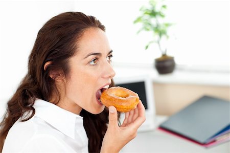 Smiling hispanic businesswoman eating a doughnut in her office Stock Photo - Budget Royalty-Free & Subscription, Code: 400-04220854