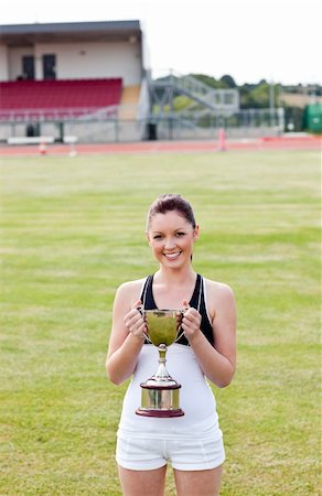 Happy female athlete holding a trophy in a stadium Photographie de stock - Aubaine LD & Abonnement, Code: 400-04220909
