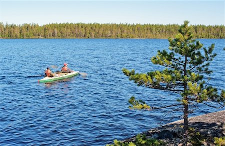 simsearch:400-04804407,k - Rocky coast of lake with a pine, on blue  lake tourists floatt on  canoe Stock Photo - Budget Royalty-Free & Subscription, Code: 400-04223447