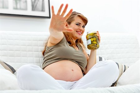 simsearch:400-05911635,k - Embarrassed beautiful pregnant woman sitting on sofa at home and  holding  jar of pickles in hands Foto de stock - Super Valor sin royalties y Suscripción, Código: 400-04234838